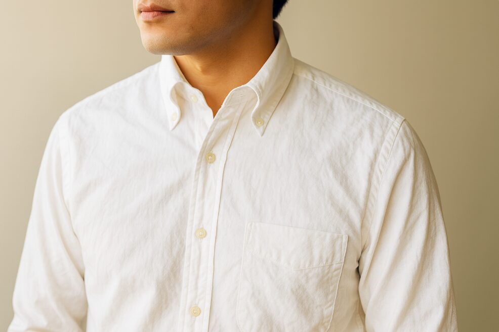 高級綿100%素材特有の自然なシワと風合いを示す、高品質な白いドレスシャツのクローズアップ。